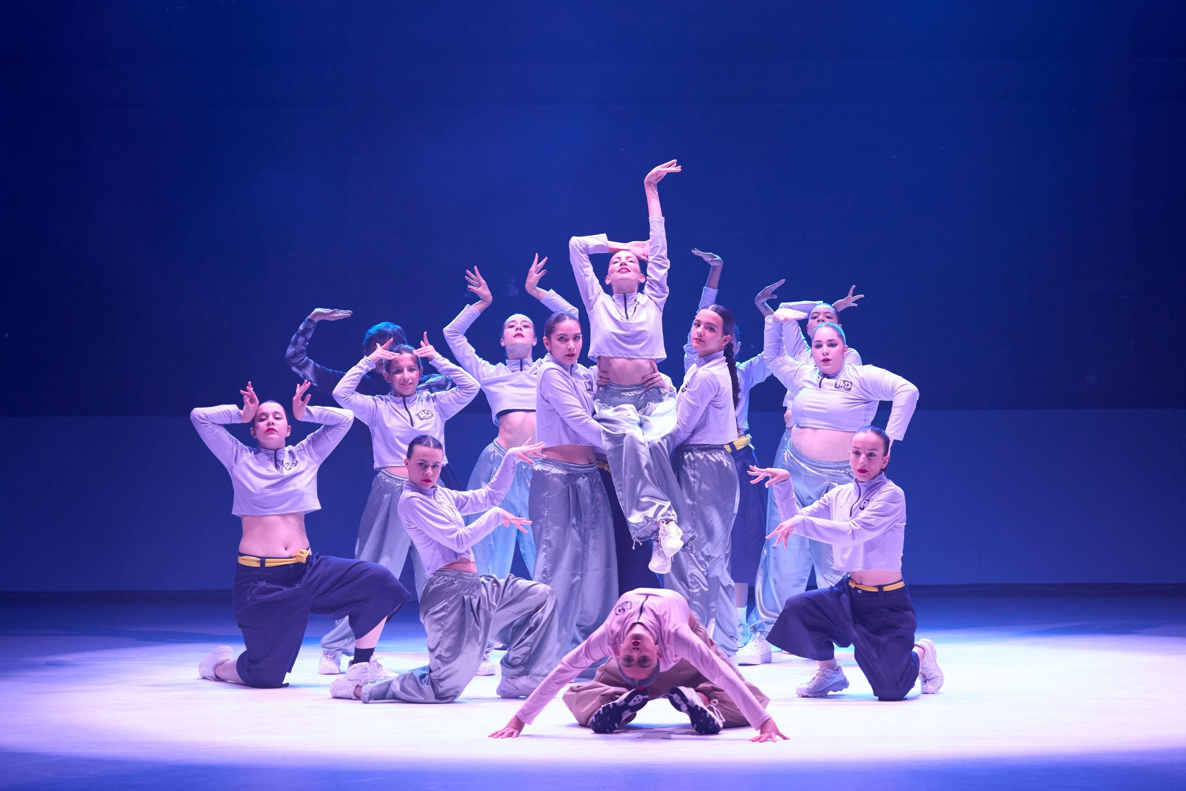 Grupo da Academia R&D em pose final em palco, com luz azul